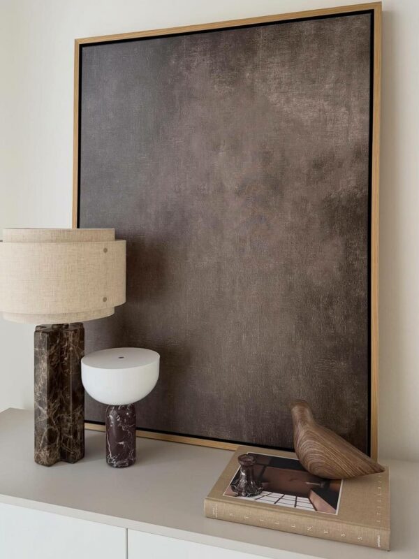 modern bruin schilderij op en kast naast twee bruine tafellampen