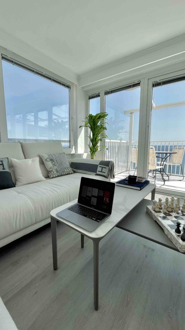 een lichte woonkamer met witte bank en salontafel met laptop